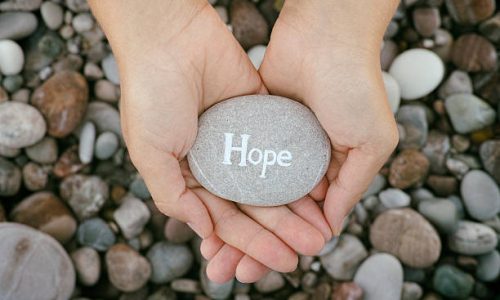 Hope. Woman holding stone with the word Hope in her palms. Close up.